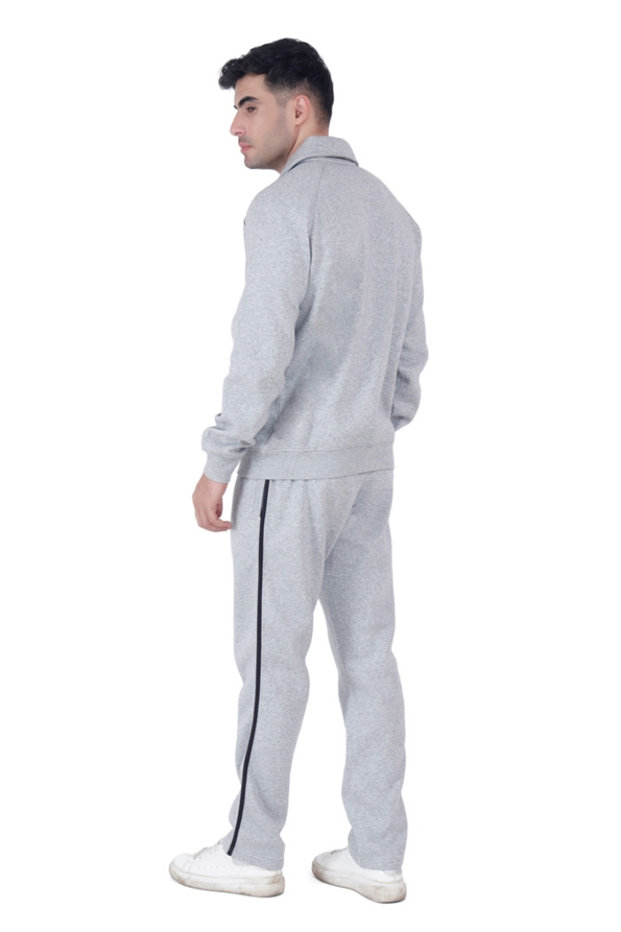 A man in Trufit’s Grey Grindle tracksuit with black side piping, shown from the back while turning his head slightly, wearing white sneakers against a plain white background